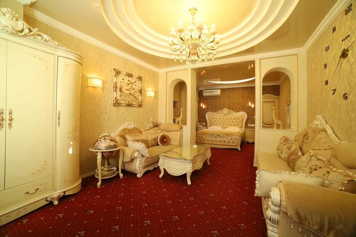 Un salón lujoso con muebles ornamentados, una araña y una alfombra roja.
