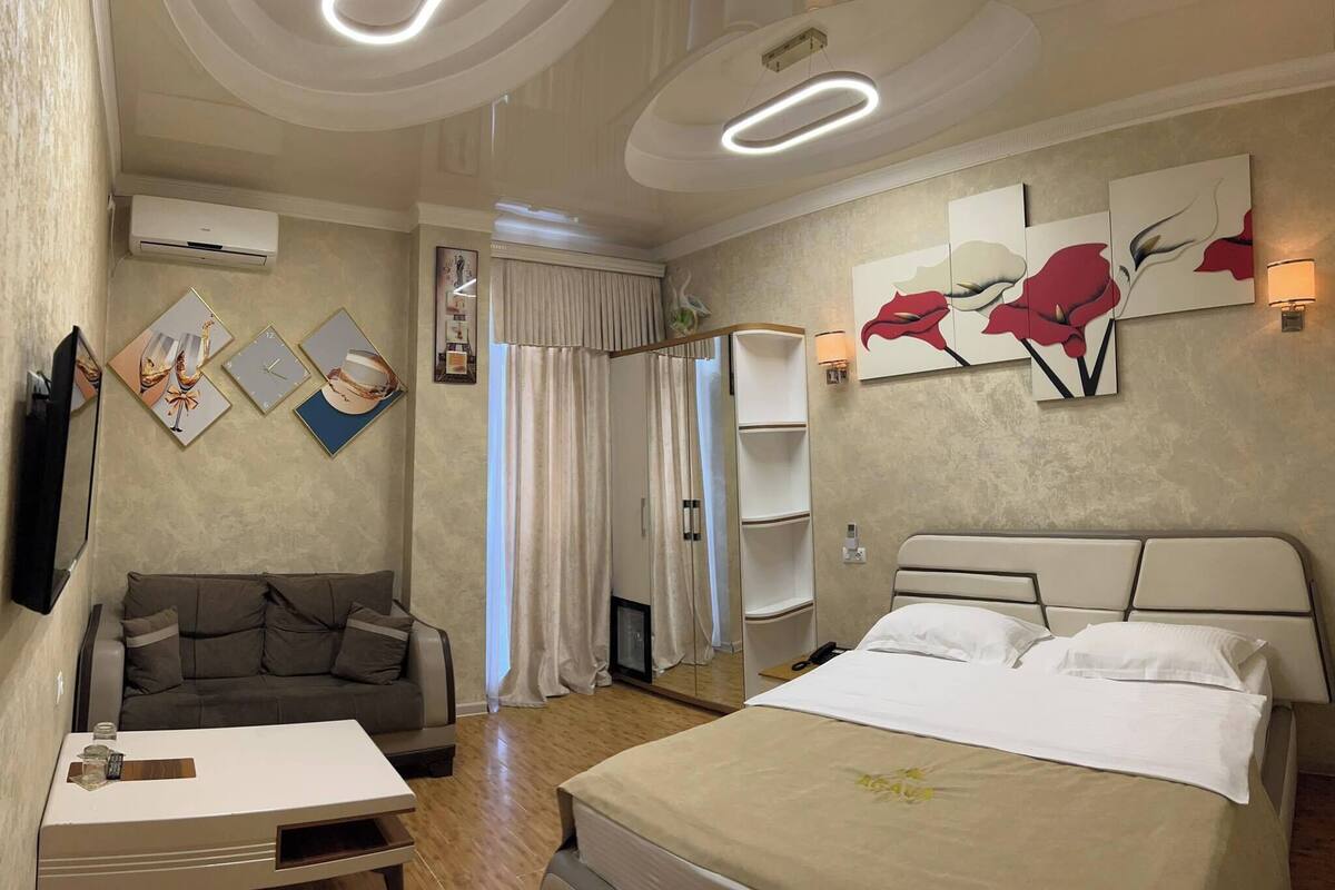 Una habitación de hotel con cama, sofá, una mesita y obras de arte en las paredes.