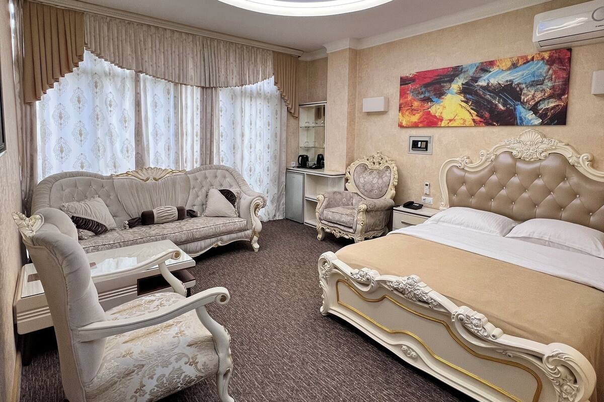 Un dormitorio lujoso con una cama grande, un sofá, una silla y un tragaluz en el techo.