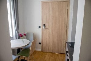 A room with a wooden door, a round table with a green chair, and a vase with flowers. - Zagreb City Vibe Apartments & Rooms (Zagreb)