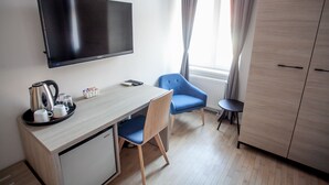 A hotel room with a flat-screen TV mounted on the wall, a wooden desk with a chair, a small table with a kettle and cups, and a wardrobe. - Zagreb City Vibe Apartments & Rooms (Zagreb)