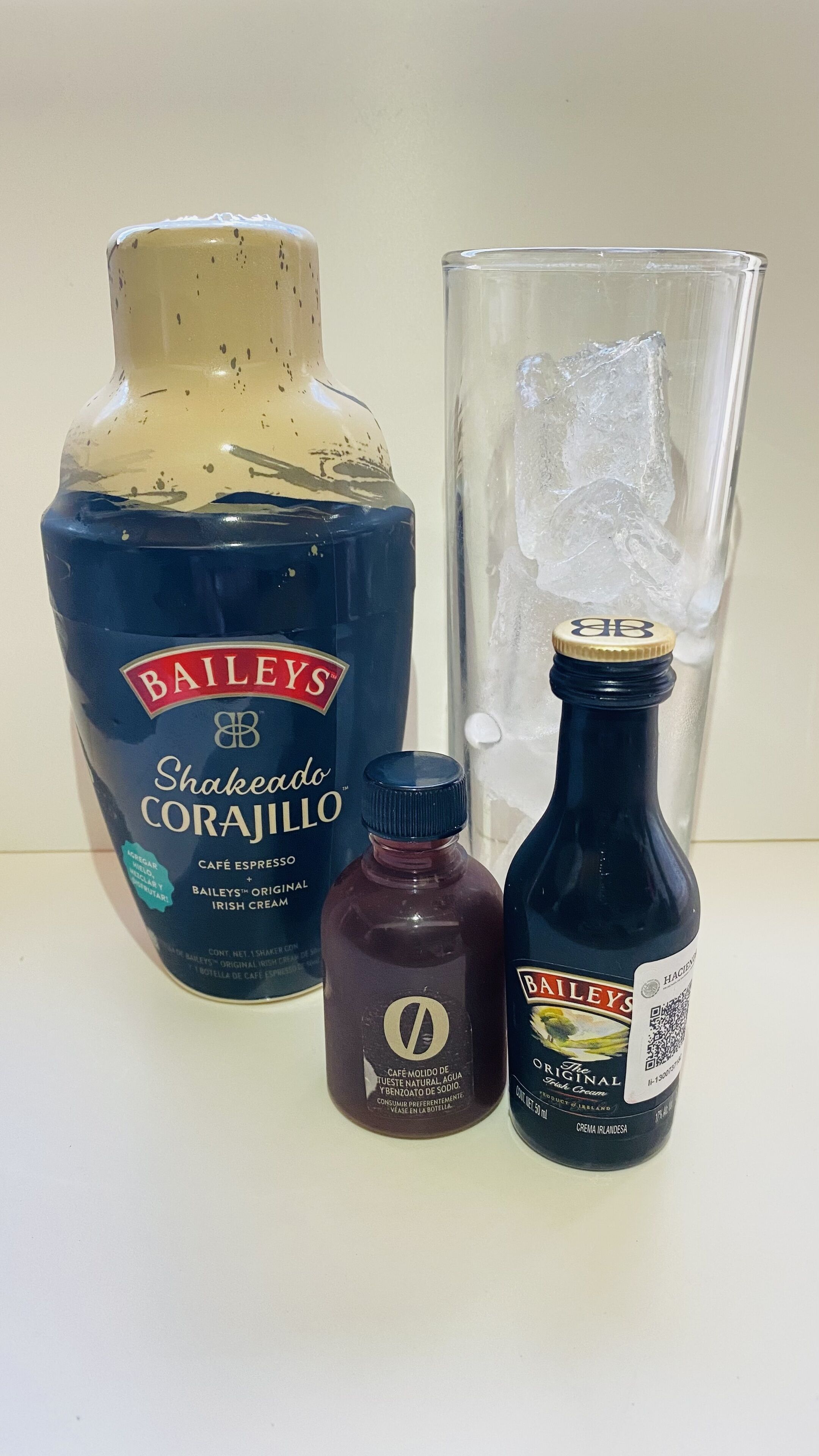 Una botella de Bailey's Shakedown Corajillo, una botella pequeña y oscura, y una botella de Bailey's Original Irish Cream.