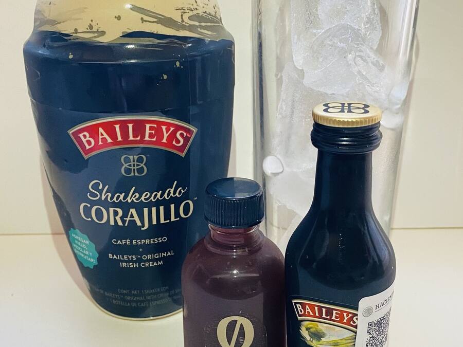 Una botella de Bailey's Shakedown Corajillo, una botella pequeña y oscura, y una botella de Bailey's Original Irish Cream.