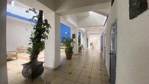 A corridor with tiled flooring, potted plants, a bench, and doors. - Hotel Bahia (Guadalajara)