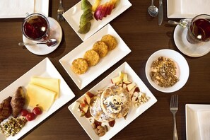 Desayuno con diversas opciones, como panqueques, cruasanes y fruta.