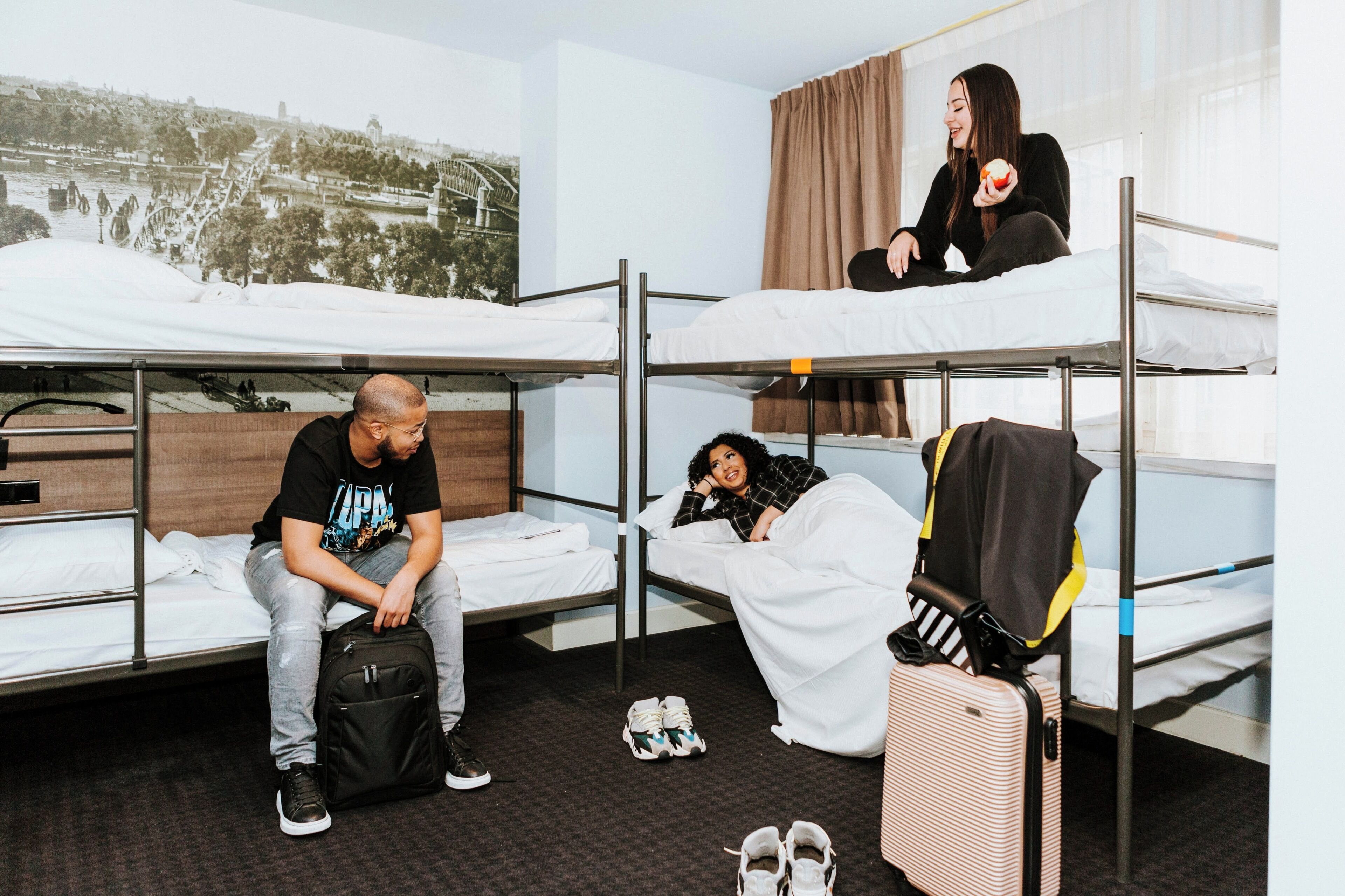 Habitación de residencia con literas, una maleta y un par de zapatillas en el suelo.