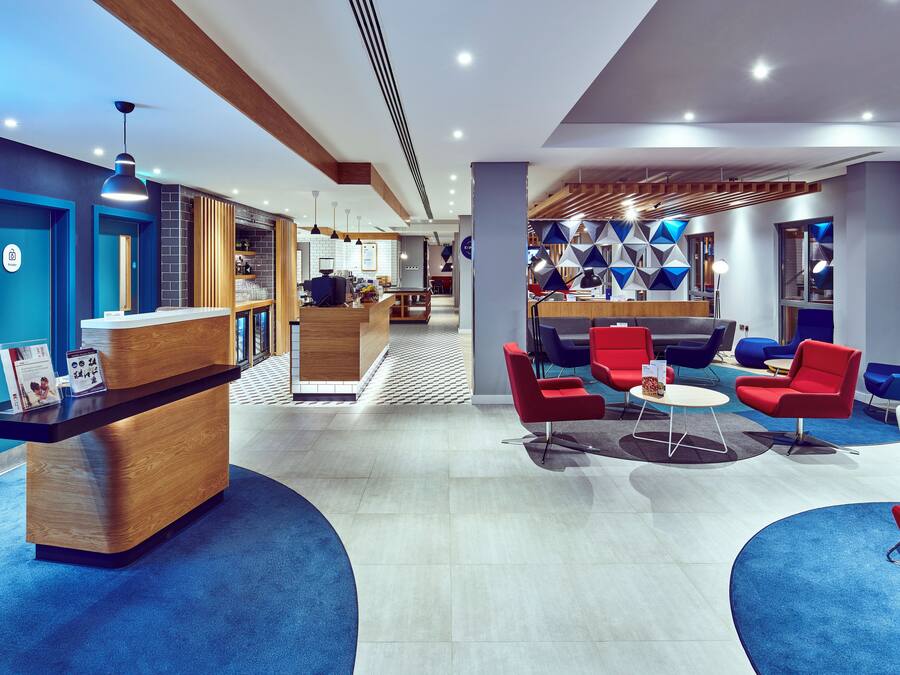 Un moderno vestíbulo de hotel con una recepción, zona de estar y un bar.