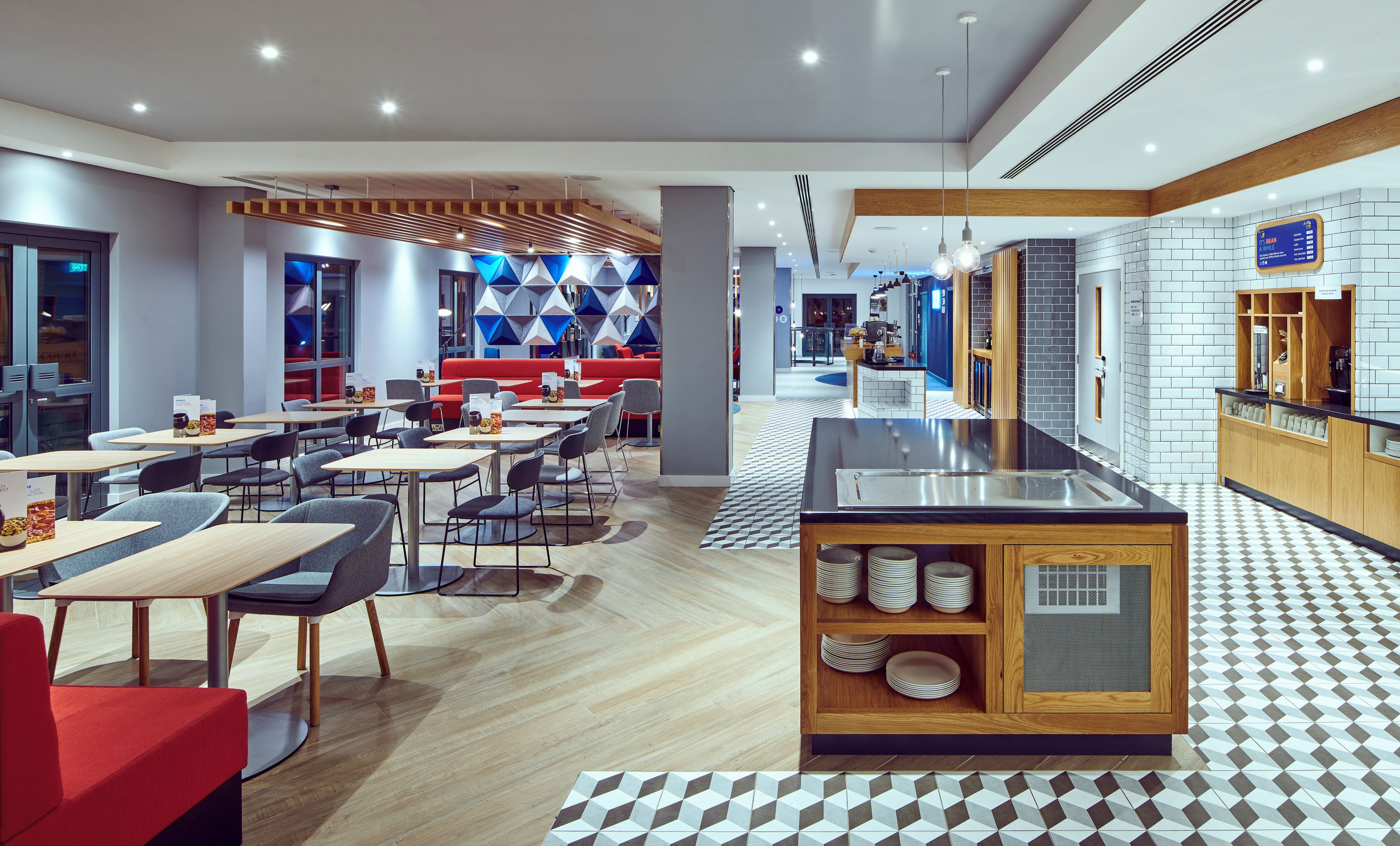 Un interior de restaurante moderno con varias zonas de estar, una barra central y un tablero de menú visible.