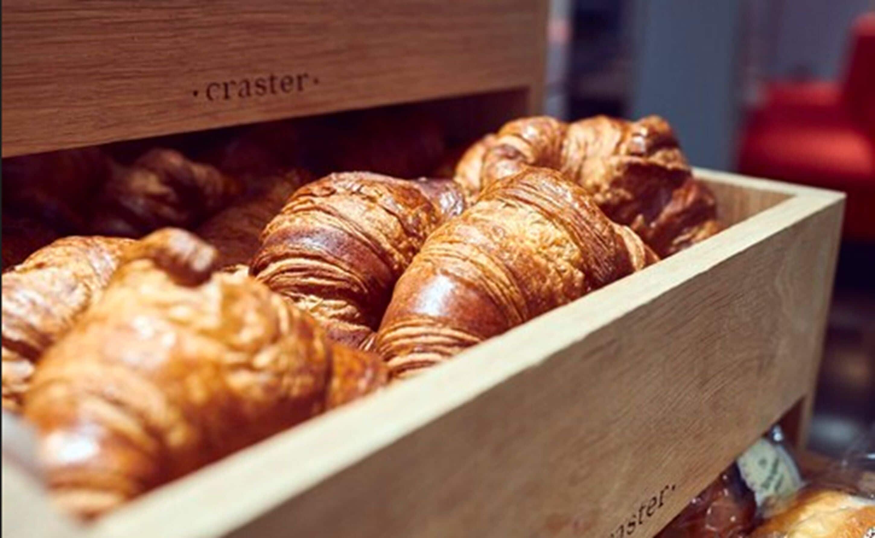 A wooden box containing several croissants.