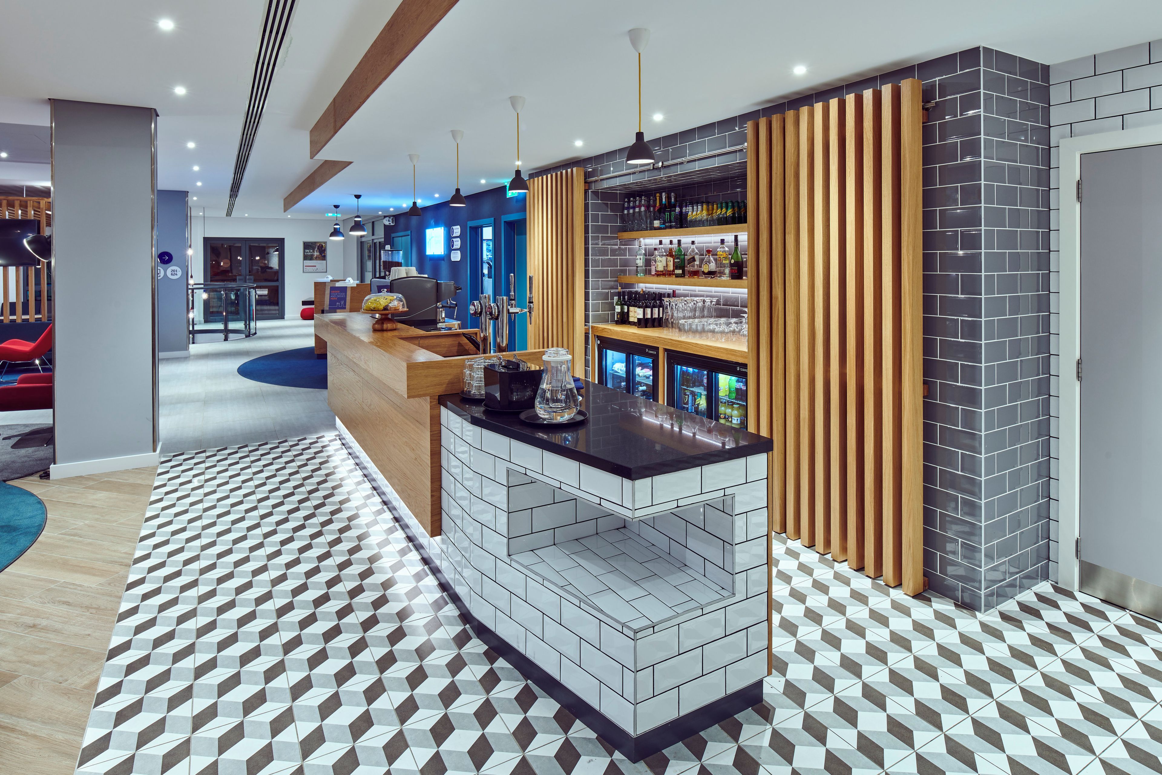 A modern bar area with a counter, shelves of bottles, and a patterned floor.