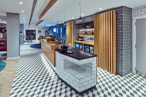 Un área de bar moderna con mostrador, estantes llenos de botellas y piso estampado.