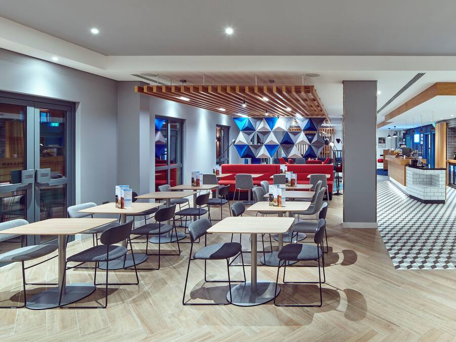 Ein modernes Restaurant mit mehreren Tischen, Stühlen, einer Bar und einem Wanddesign mit Muster.