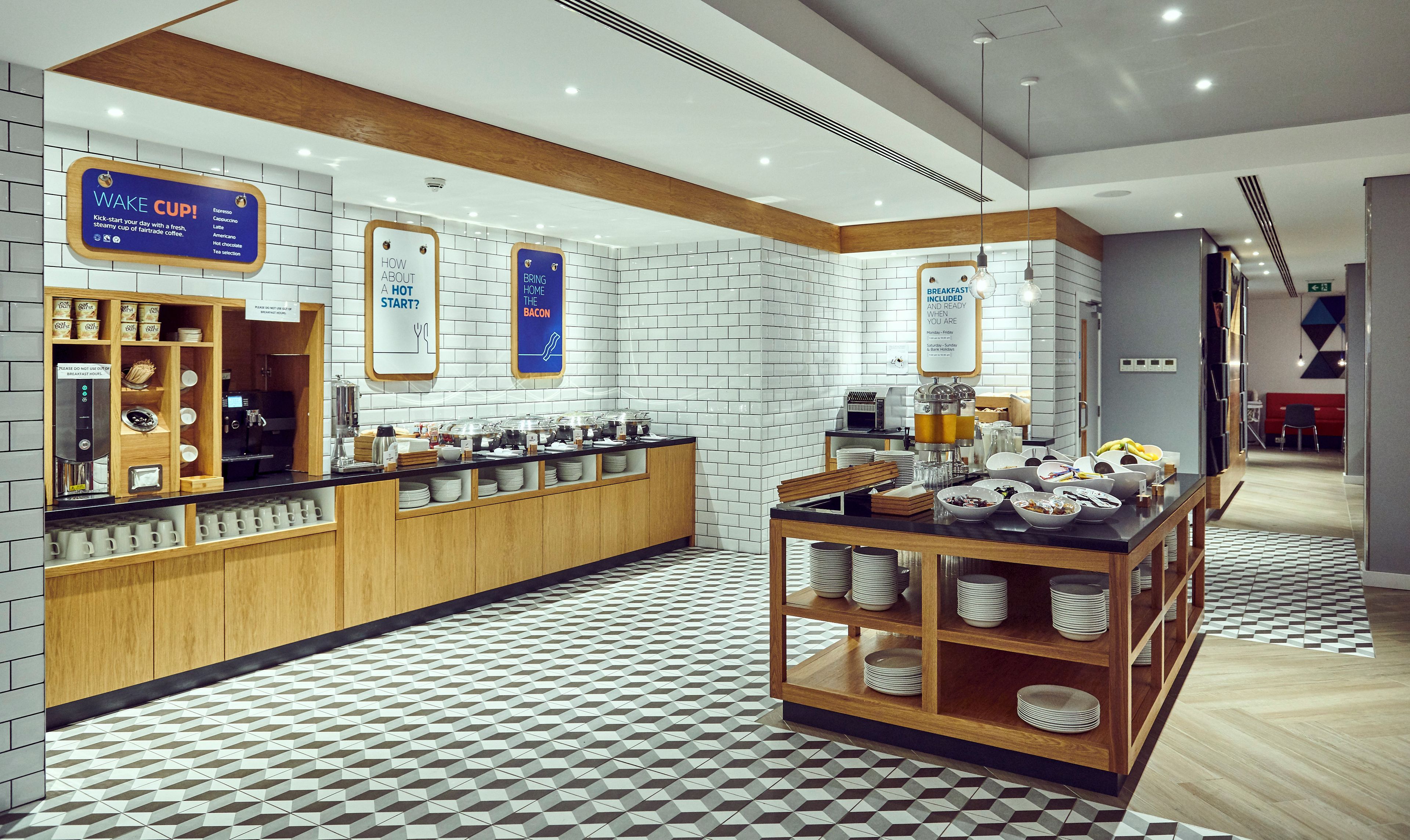 Un espace moderne dédié au petit-déjeuner, comprenant un coin café, un panneau indiquant le petit-déjeuner et un autre panneau précisant que le petit-déjeuner est inclus.