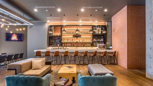 Zona de bar moderna con pared de ladrillo, muebles de madera y una variedad de botellas en estantes.