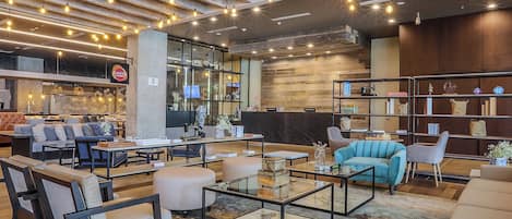 Un interior moderno con zonas de estar, una recepción y un restaurante visible llamado 'SANTA'.