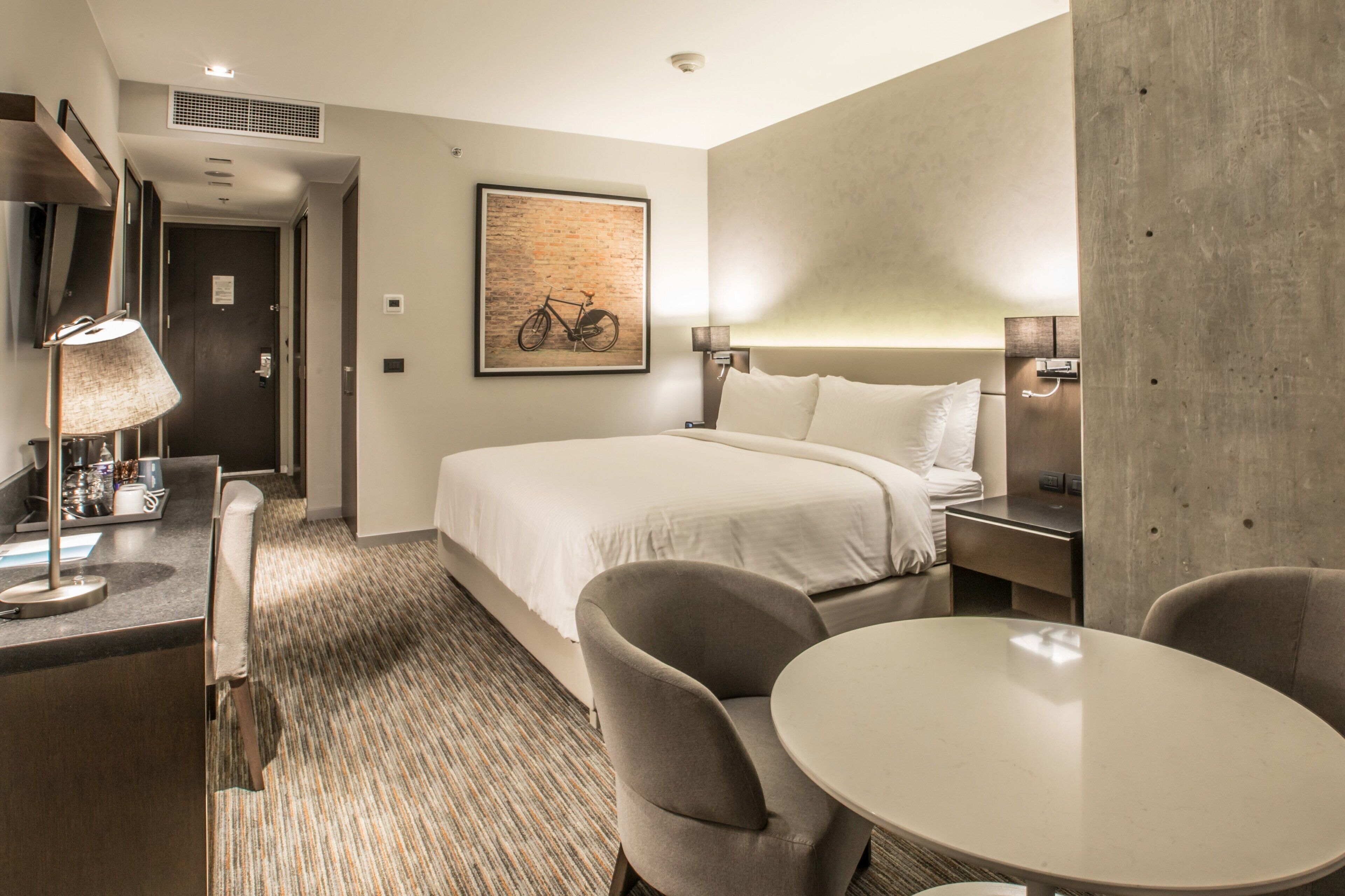 Una habitación de hotel con cama, escritorio, silla y mesa redonda.