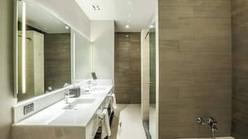 Un baño moderno con un espejo grande, dos lavamanos, una ducha y una bañera.