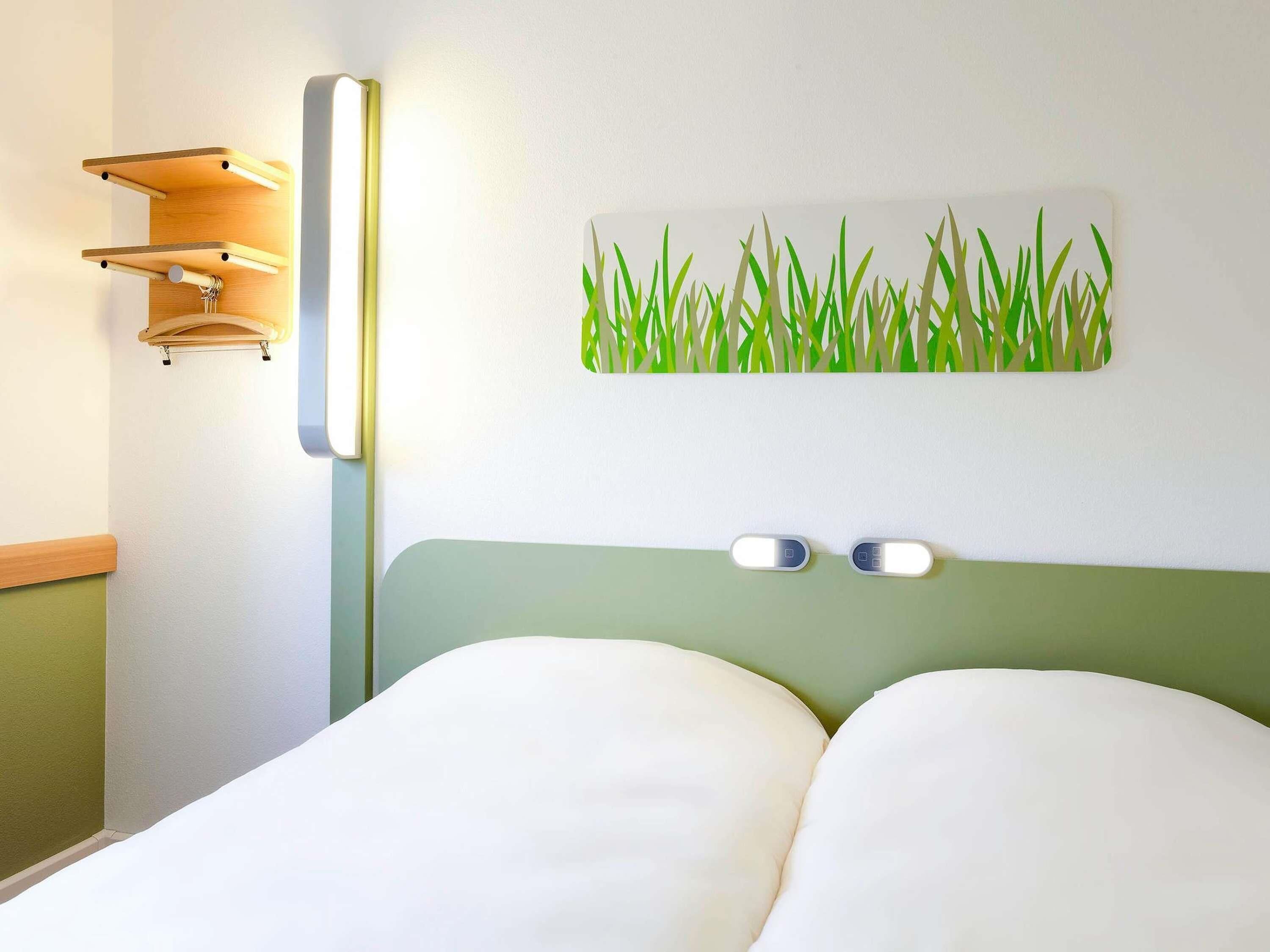 Habitación de hotel con cama, lámpara de pared y una obra de arte decorativa.