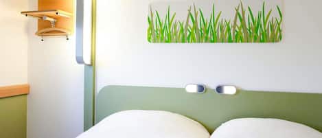 Habitación de hotel con cama, lámpara de pared y una obra de arte decorativa.