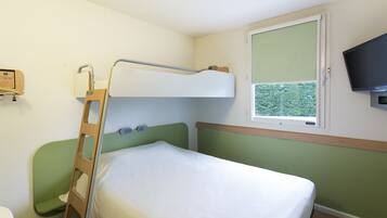 A bunk bed with a ladder, a bedside table, a window with a view, and a television mounted on the wall.