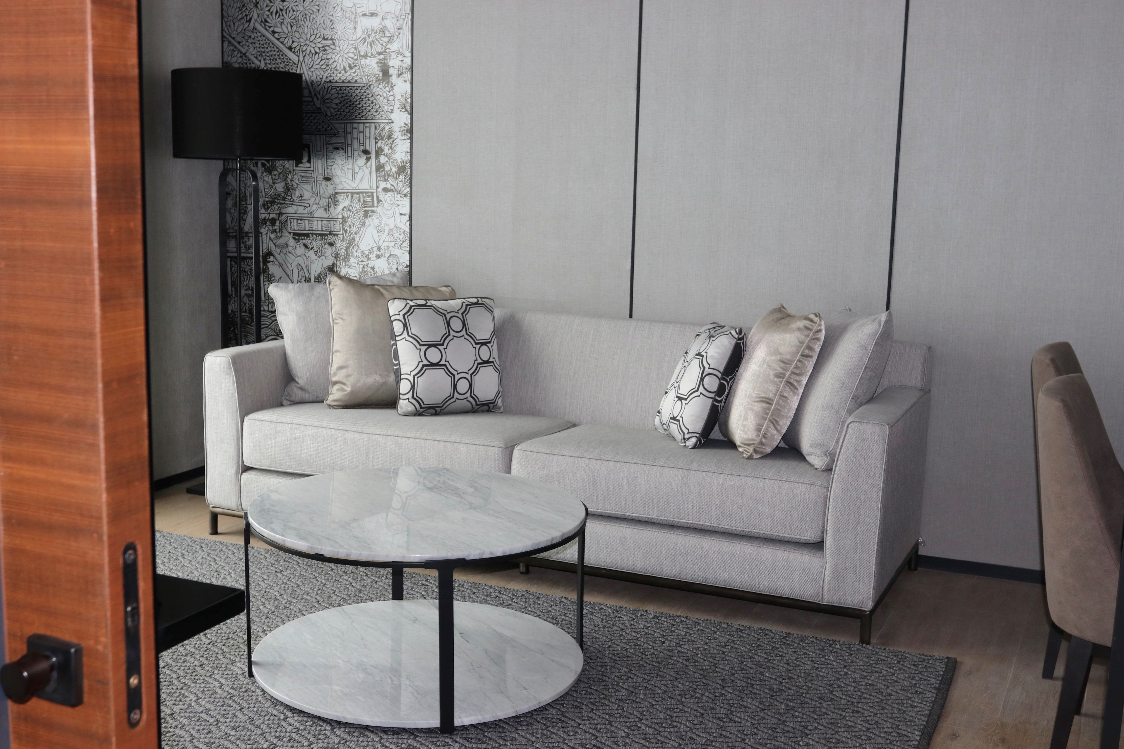 A modern living room with a grey sofa, a round coffee table, and patterned cushions.