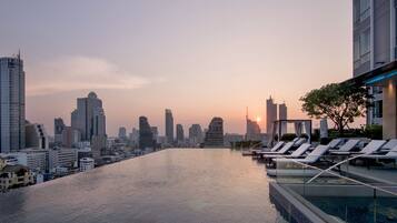 A rooftop infinity pool with a city skyline view at sunset.