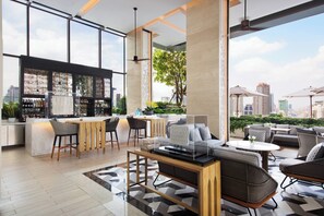A modern bar area with a bar counter, seating, and a city view. - Bangkok Marriott Hotel The Surawongse (Bangkok)