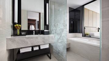 A modern bathroom with a marble vanity, a large mirror, and a bathtub.