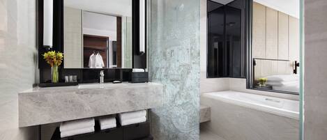 A modern bathroom with a marble vanity, a large mirror, and a bathtub.