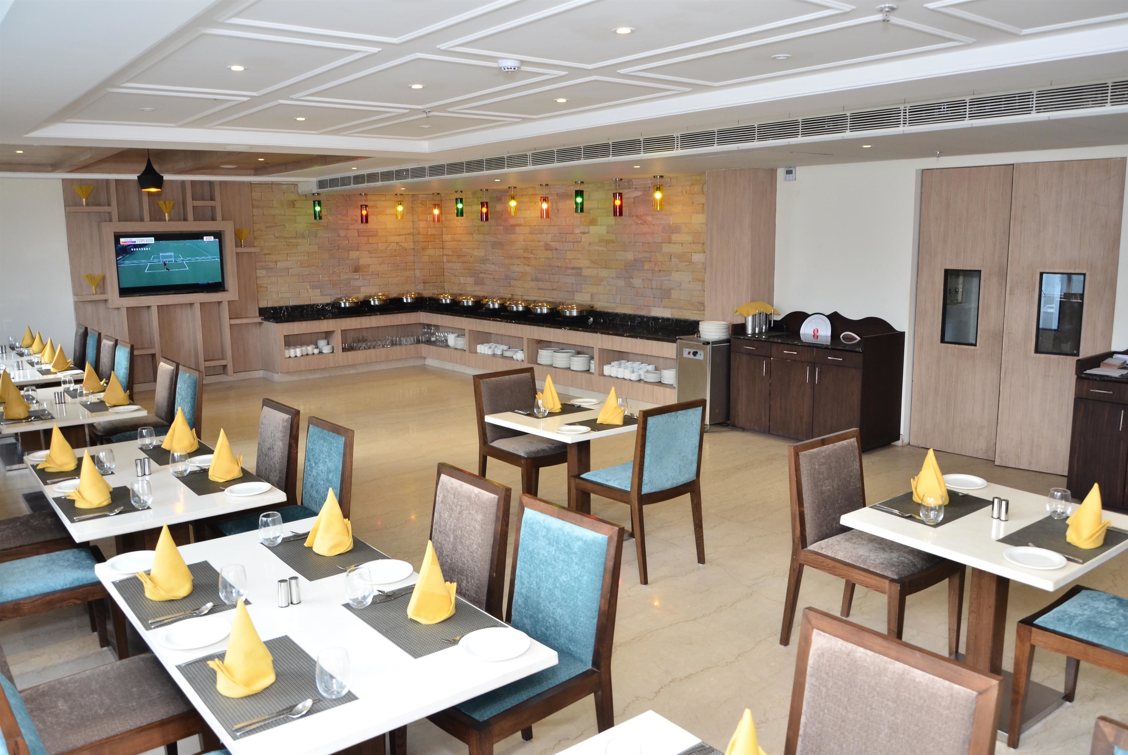 Un restaurante con varias mesas, sillas y una pantalla de televisión.