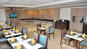 Un restaurante con varias mesas, sillas y una pantalla de televisión.