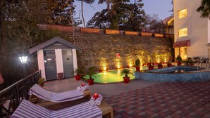 Ein Poolbereich mit Liegestühlen, einem kleinen Gebäude und einer Steinmauer.