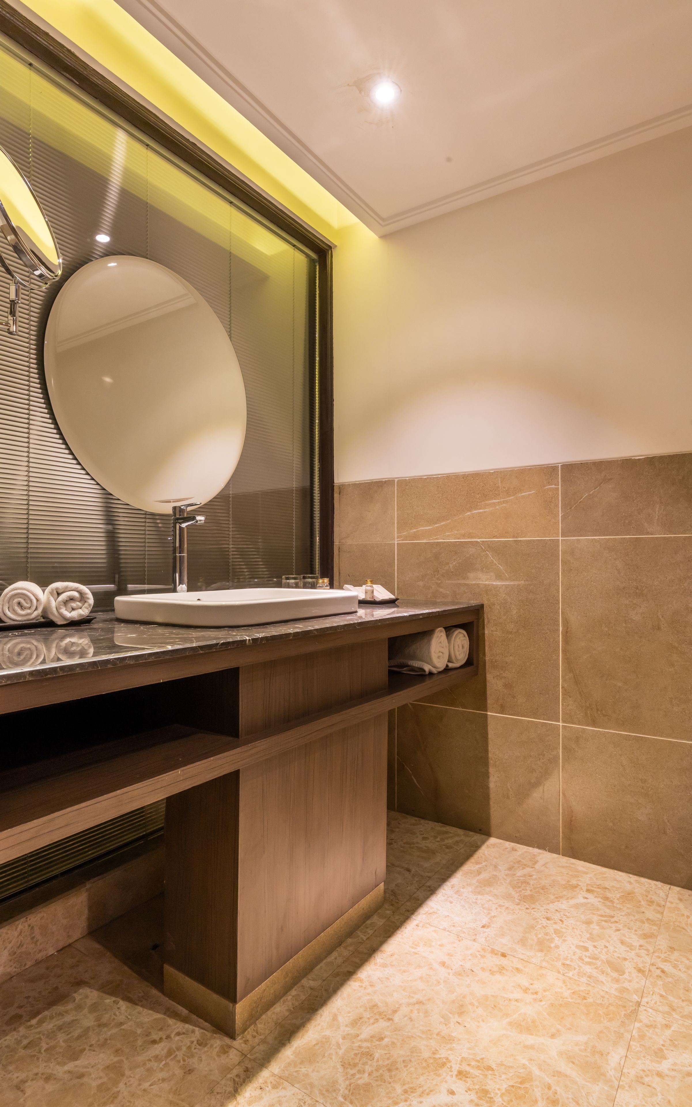 Un baño moderno con un espejo grande, un lavamanos y un mueble de tocador con toallero.