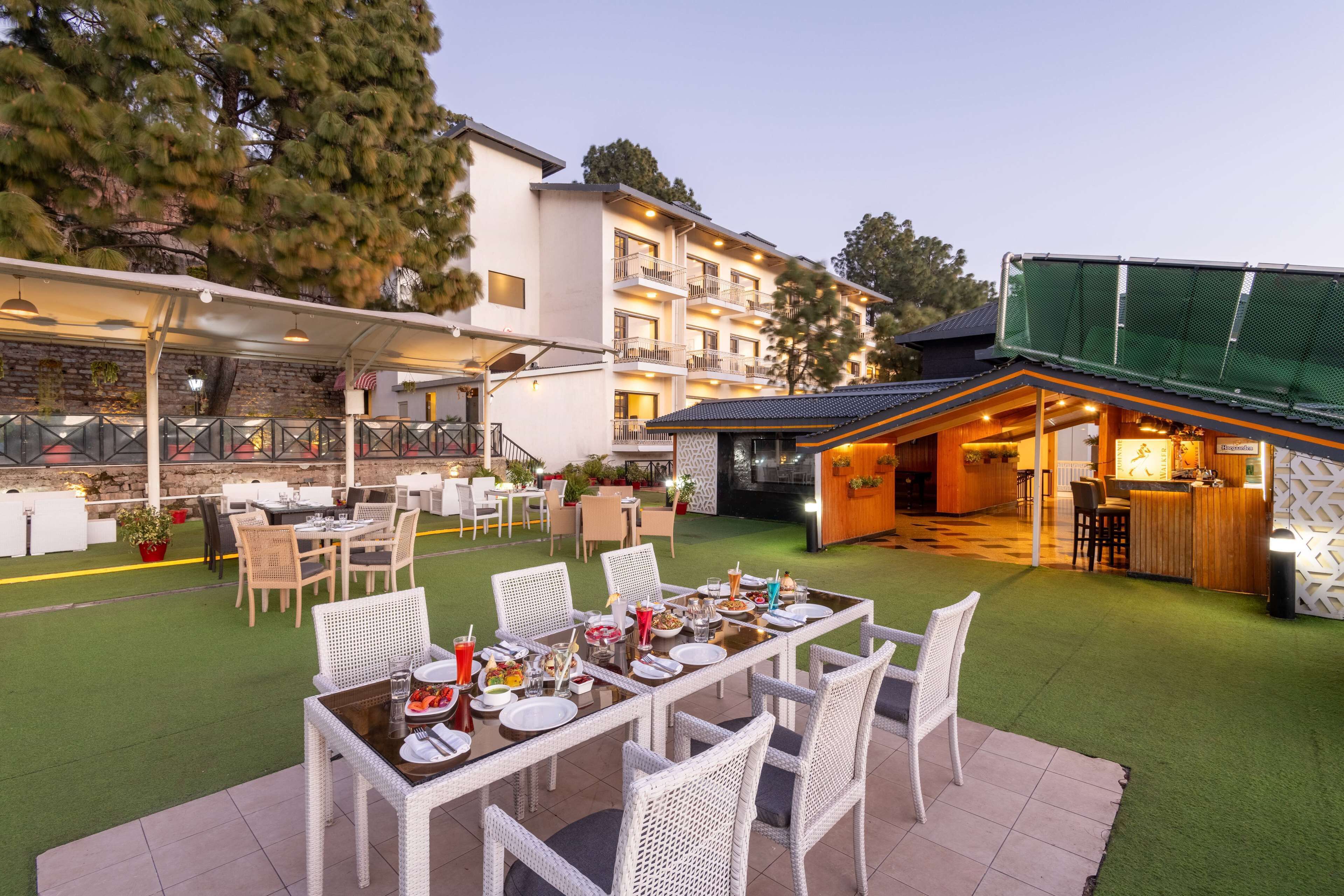 Un espace de restauration en plein air avec des tables et des chaises, un bar et un bâtiment doté de plusieurs balcons.