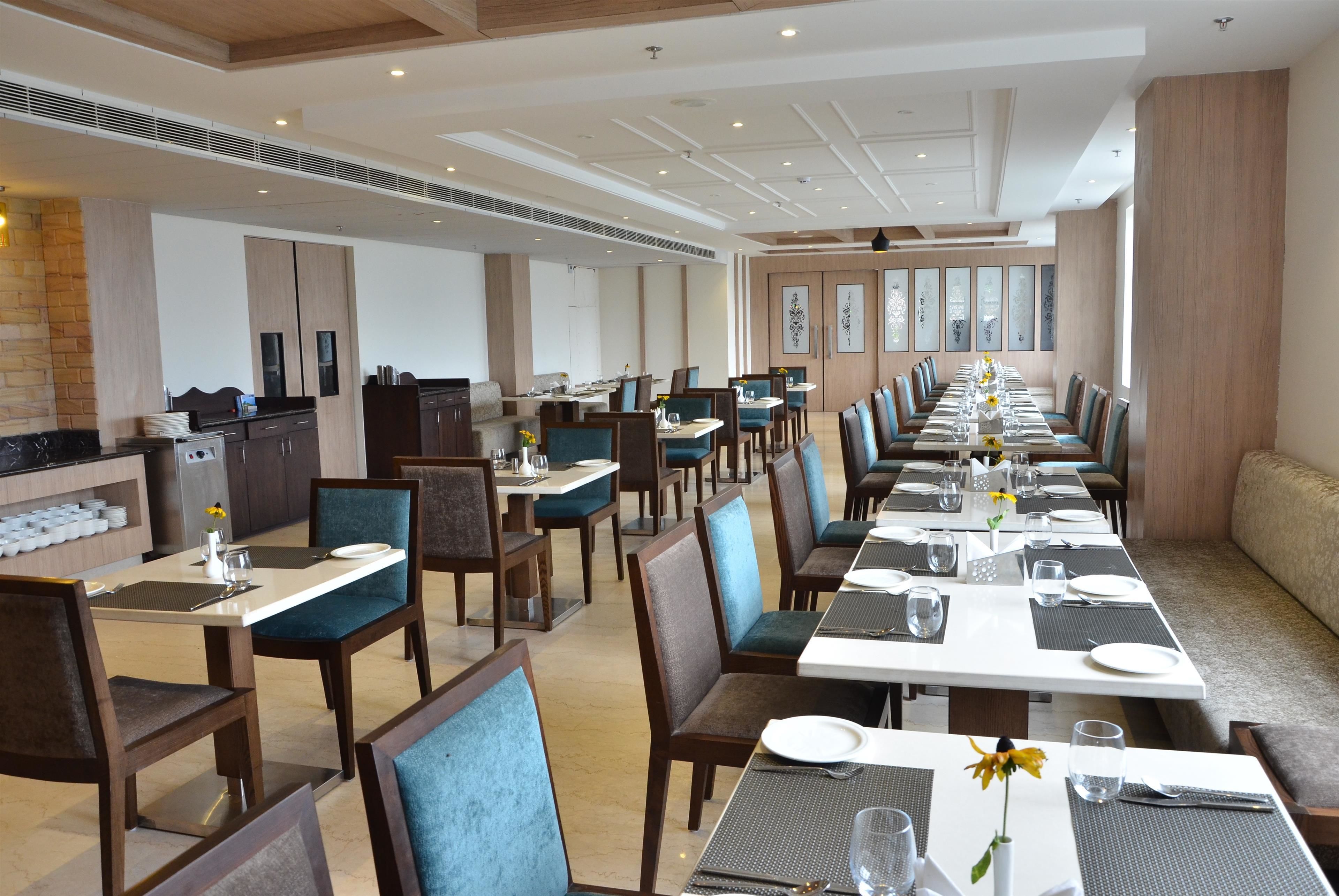 A spacious dining area with multiple tables and chairs, a kitchen area, and a seating area with a sofa.