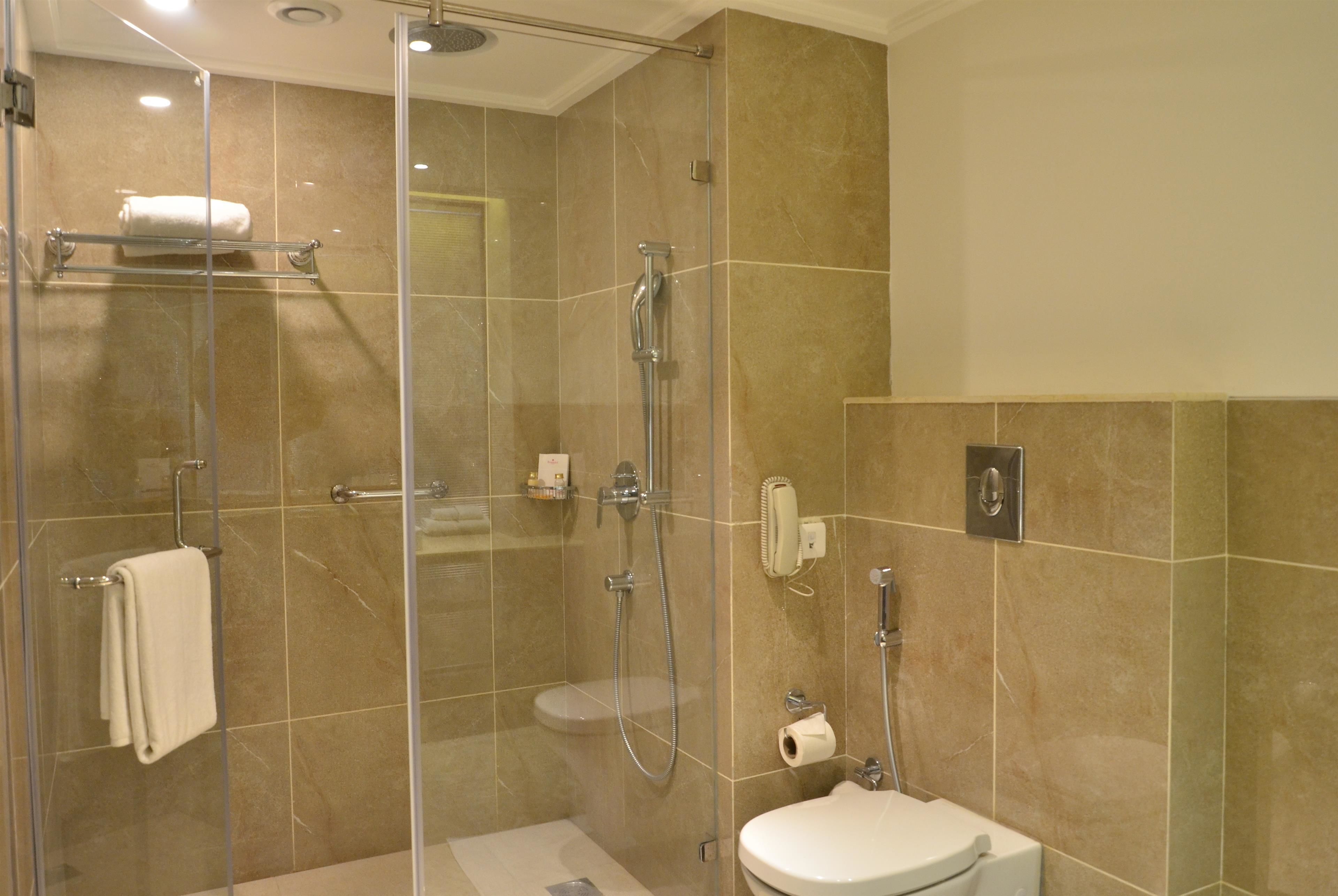 Ein modernes Badezimmer mit einer Duschkabine, Toilette und Handtuchhalter.