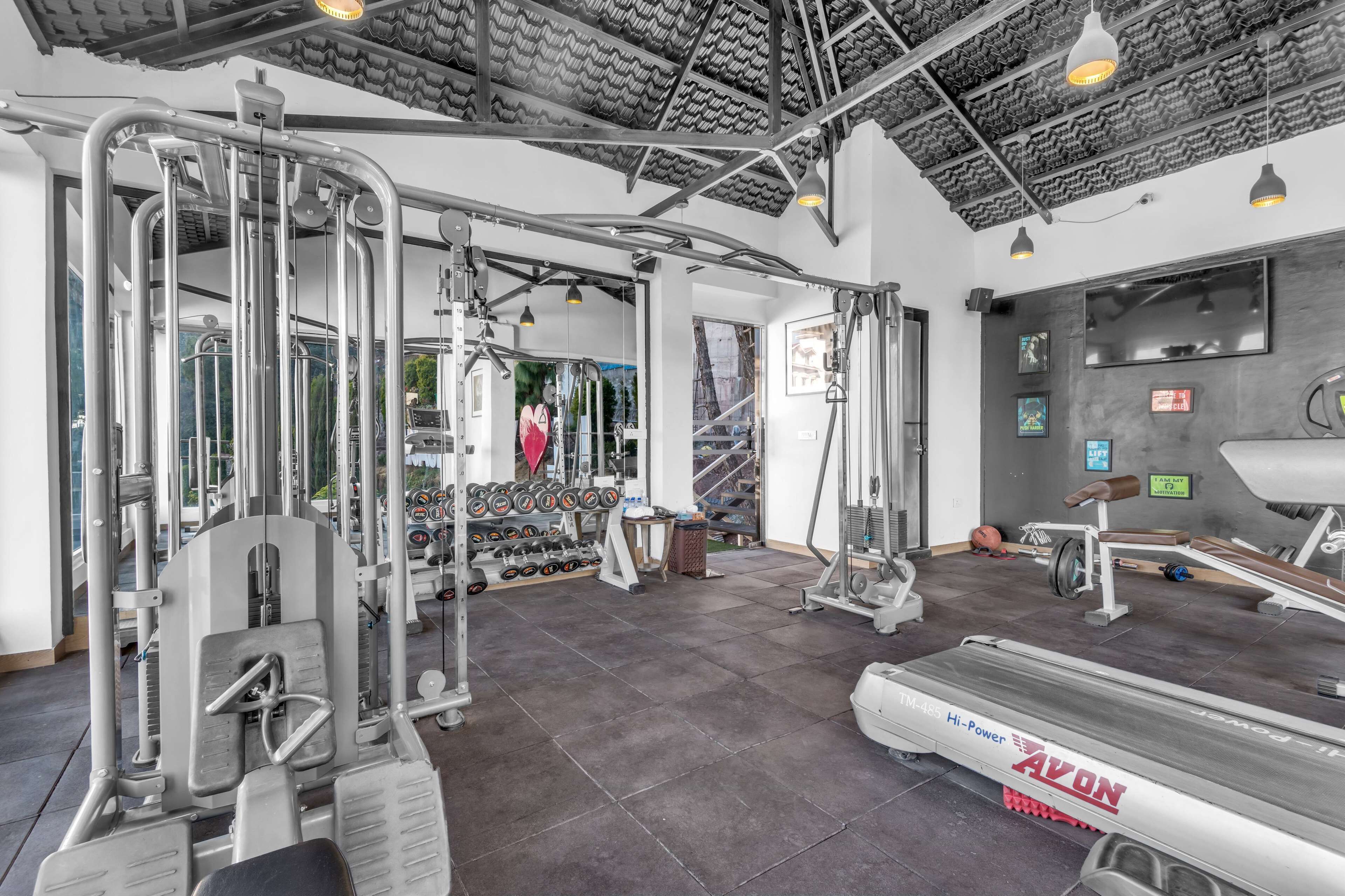 A gym with various exercise equipment, a treadmill, and a wall-mounted TV.