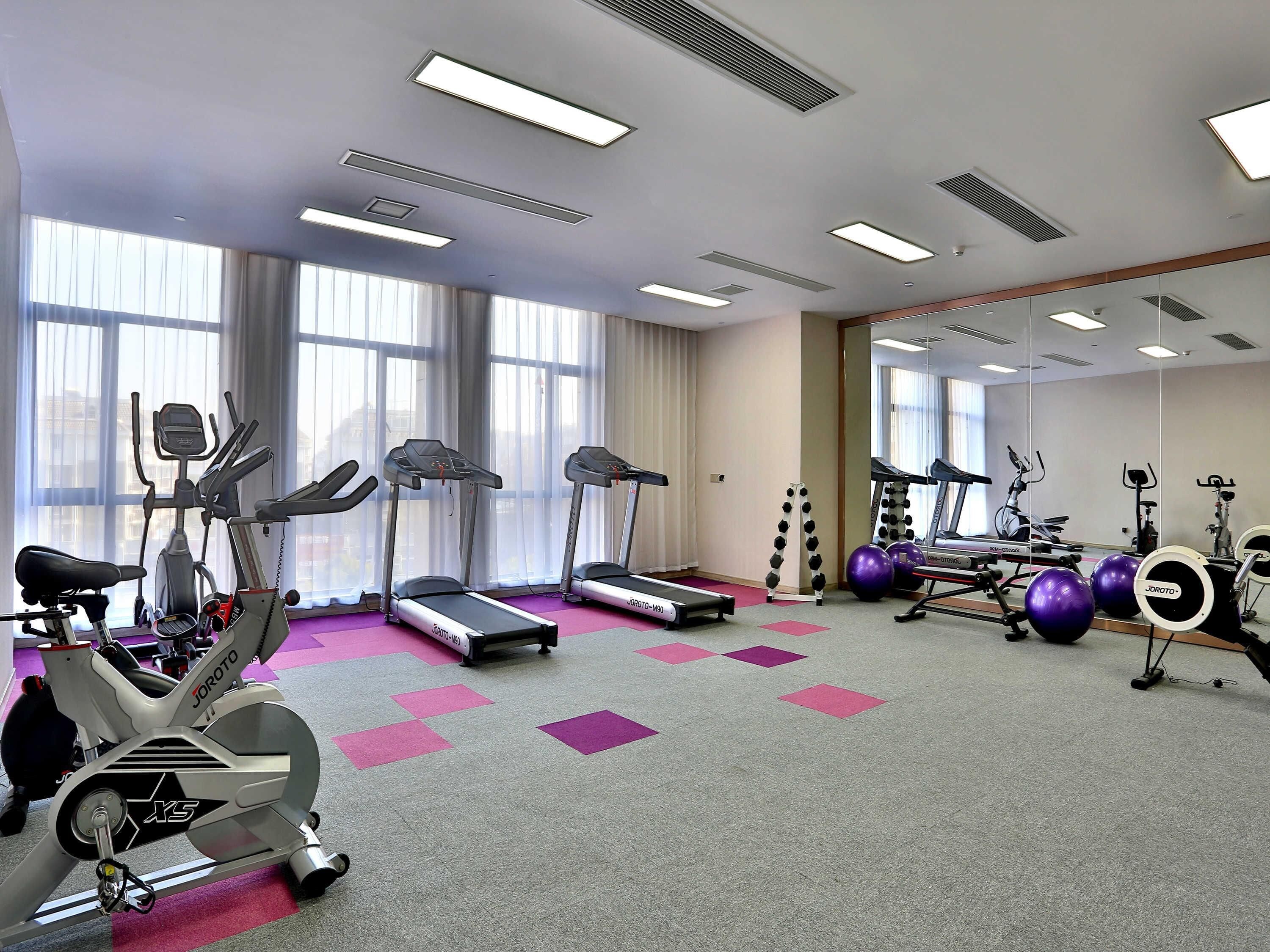 A gym with treadmills, stationary bikes, and exercise balls.