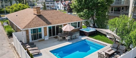Un jardin à l’arrière d’une maison, avec une piscine, du mobilier de jardin et un jacuzzi.