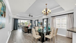 A spacious dining area with a glass table and chairs, a chandelier, and a view of the outdoors. - Sandy Ridge Retreat | 3BR, 3 Bath Condo w/ Reunion Resort Views Near Orlando Theme Parks (Reunion)