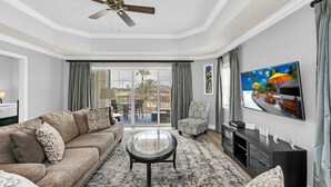 A spacious living room with a large sofa, a coffee table, and a television mounted on the wall. - Sandy Ridge Retreat | 3BR, 3 Bath Condo w/ Reunion Resort Views Near Orlando Theme Parks (Reunion)