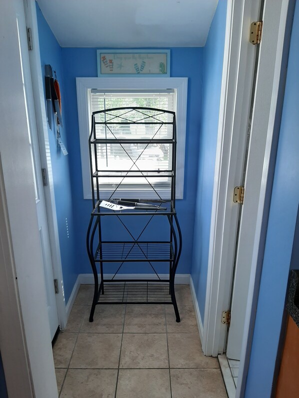 A narrow hallway with a black metal shelf unit against a blue wall, a window with a view of the outside, and a door on the right. - Q St. Less traffic!!! Gas grill.
Rare find. Five bedroom with fenced in yard! (Hampton)