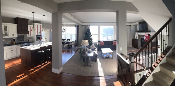 A spacious living area with a fireplace, a dining table, and a Christmas tree.