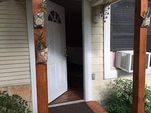 Enter a serene space with a partially open door, revealing a cozy interior, complete with a planter and wind chime.