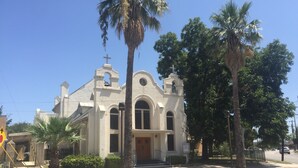 Een kerk met een klokkentoren, boogvensters en een kruis bovenop.