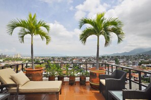 A terrace with two palm trees, a lounge chair, and a table. - Villa  Europa - A Modern Private Home - Enjoy Views, Downtown and Beaches (Puerto Vallarta)