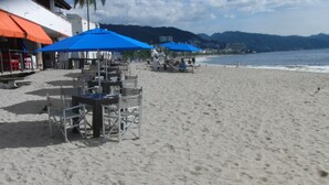Un restaurante frente al mar con mesas al aire libre y sombrillas.