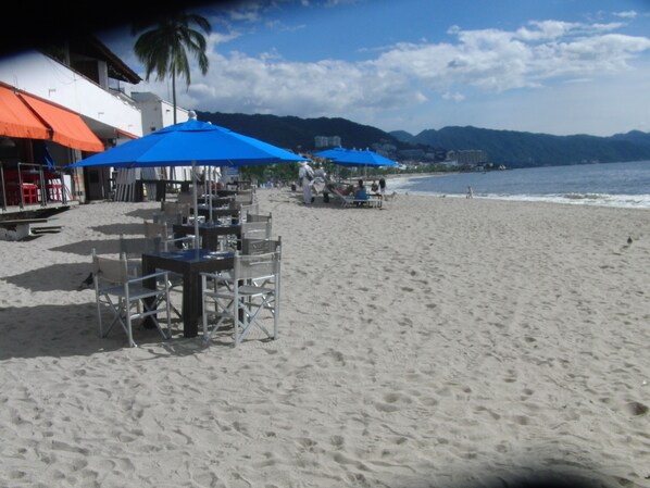 A beachside restaurant with outdoor seating and umbrellas, overlooking the ocean. - Villa  Europa - A Modern Private Home - Enjoy Views, Downtown and Beaches (Puerto Vallarta)