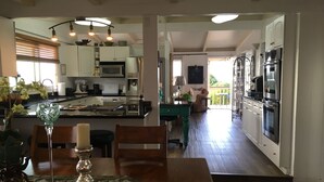 A modern kitchen with white cabinets, stainless steel appliances, and a dining area with a table and chairs.