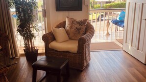 A cozy living area with a wicker sofa, a small table, and a potted plant.